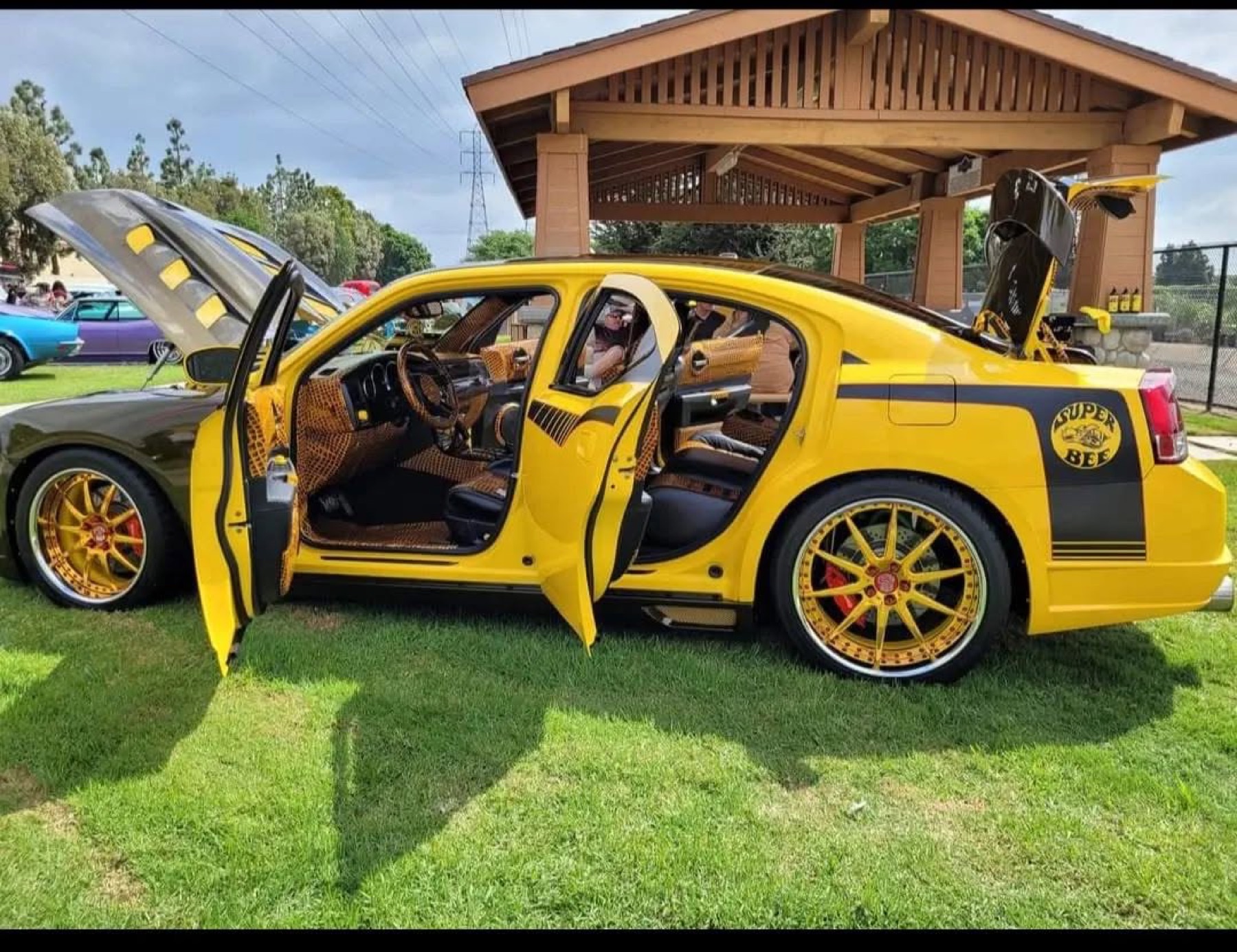The Super Bee in yellow with all doors, hood and trunk open showing the crocodile interior and gold wheels